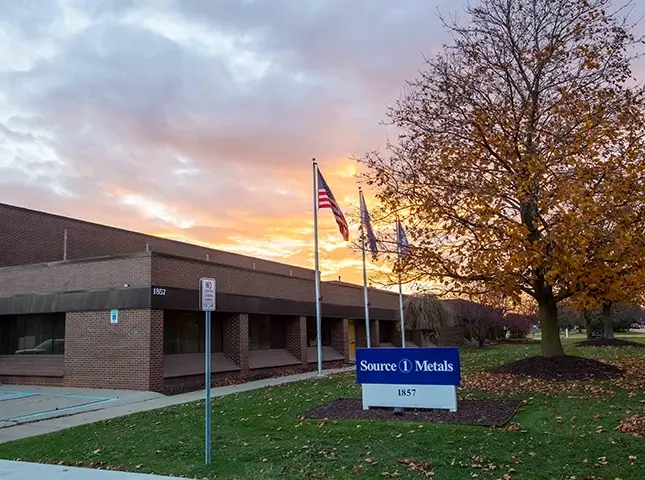 Source One Metals sign outside building with a cloudy sunset