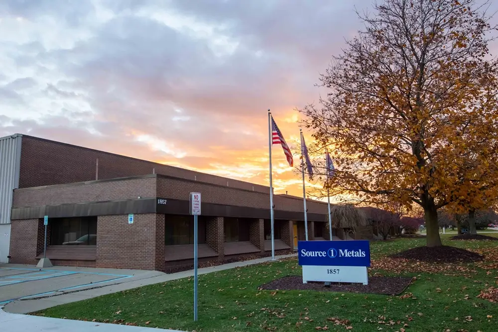 Source One Metals sign outside building with a cloudy sunset